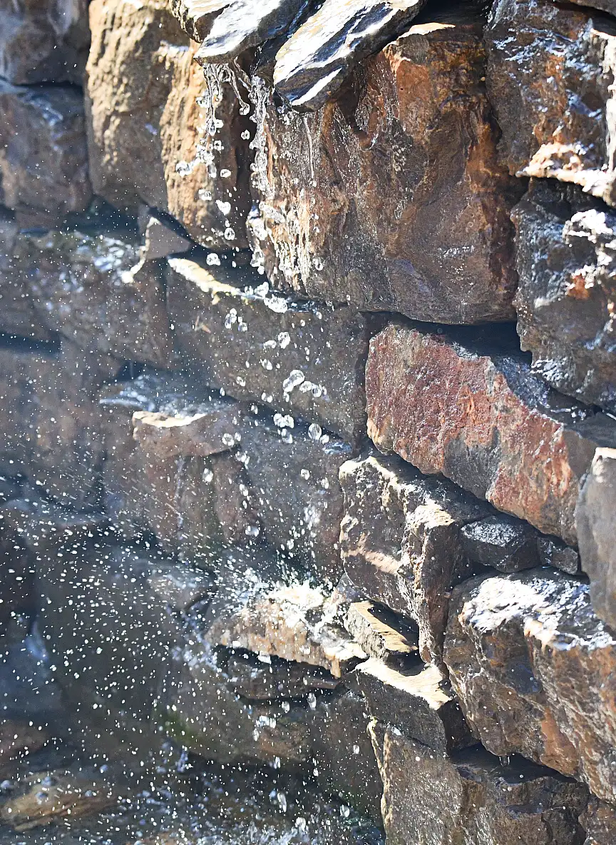 Fuente de agua con cascada de piedra natural en el jardín terapéutico de la residencia de ancianos Sol i Natura en Pallejà