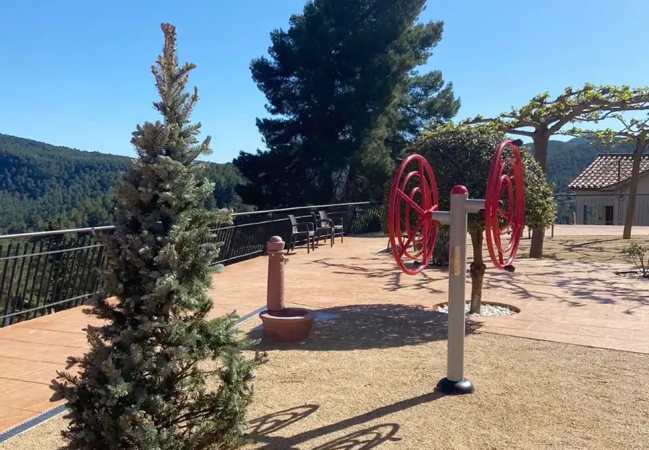 Zona de ejercicio al aire libre con aparatos y vistas a la montaña en la residencia Sol i Natura